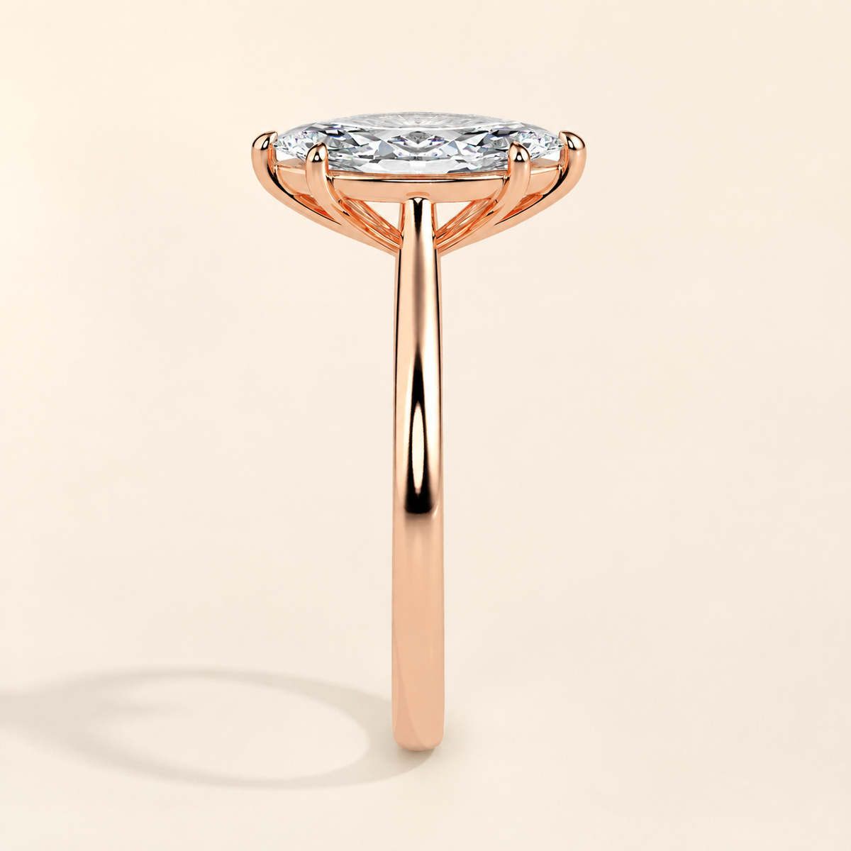 Clarice marquise solitaire ring in 18K rose gold, side view on warm ivory